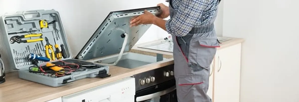 Cooktop repair technician lifting a built-in stovetop for service in Chandler, AZ