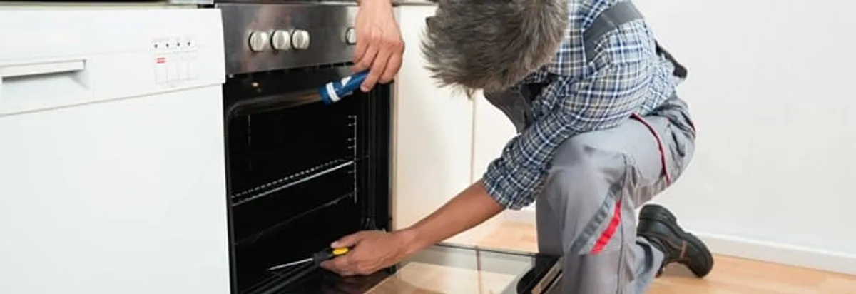 Oven repair technician inspecting and servicing an electric oven in Chandler, AZ
