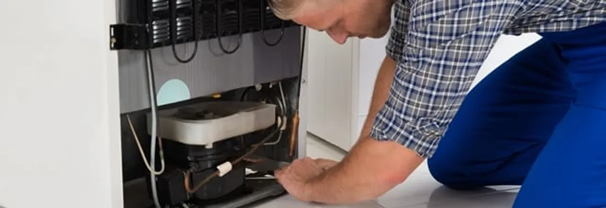 Refrigerator repair technician servicing the compressor and condenser area in Chandler, AZ