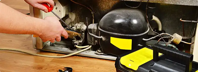 Refrigerator repair technician fixing the compressor and wiring in Chandler, AZ